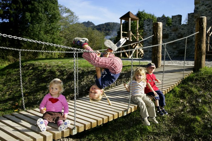 Ein echter Burggraben, ein Brunnen und viele natürliche Kletterbäume laden wie die große Schaukel und ein großer Sandbereich zum Spielen ein. Vom Spielplatz aus sieht man hoch oben auf den Falkenstein.