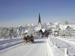 Kutschfahrt Eine Kutschfahrt durch die zauberhafte Winterwunderwelt läßt Herzen höher schlagen. Im Hintergrund die kath. Pfarrkirche St. Verena mit Frauenkapelle und die Hörnrerkette.